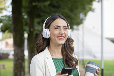 Happy woman listening music through wireless headphones - EIF02191