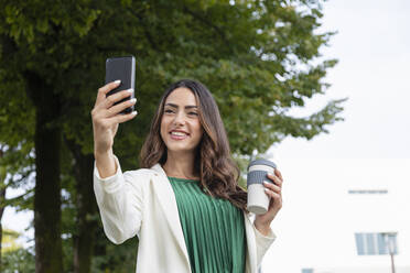 Junge Frau mit Kaffeetasse nimmt Selfie durch Smartphone - EIF02193