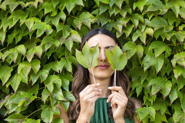 Woman covering eyes with ivy leaves - EIF02205