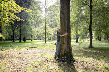 Woman hugging tree in park - EIF02232