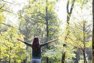 Woman with arms outstretched standing in park - EIF02240