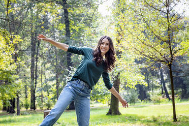 Happy woman with arms outstretched at park - EIF02243