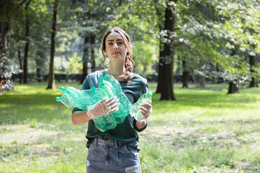 Female volunteer collecting plastic bottles in park - EIF02250