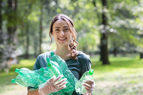 Lächelnde Umweltschützerin sammelt Plastikflaschen im Park - EIF02251