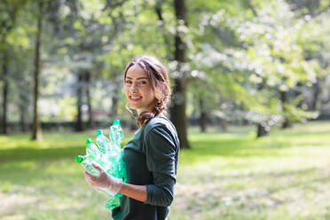 Umweltschützerin hält Plastikflaschen im Park - EIF02252