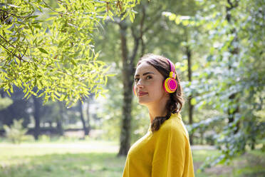 Frau hört Musik über drahtlose Kopfhörer im Park - EIF02254
