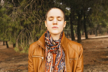 Shaved head woman with eyes closed in forest - MGRF00538