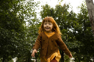 Smiling redhead girl running in park - SSGF00052