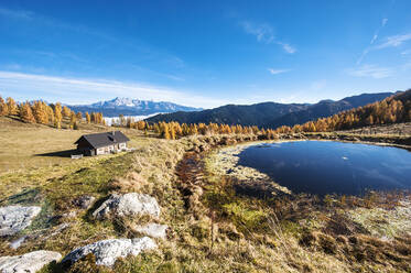 Abgeschiedene Hütte vor einem kleinen Alpensee im Herbst - HHF05789