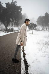 Mann, der im Winter auf der Straße im Schnee steht - RCPF01364