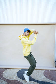 Young male performer dancing by beige backdrop - RCPF01415