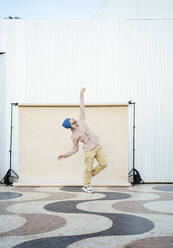 Mid adult dancer performing dance on floor by backdrop - RCPF01430