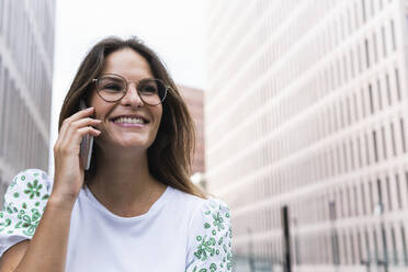 Glückliche junge Geschäftsfrau im Gespräch mit einem Smartphone - PNAF02492