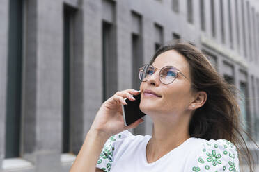 Geschäftsfrau, die mit einem Smartphone spricht und nach oben schaut - PNAF02513