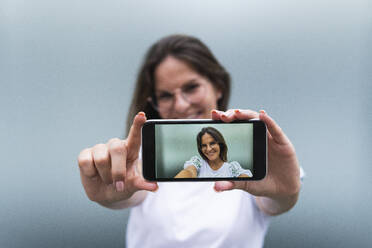 Lächelnde junge Frau beim Fotografieren mit dem Smartphone - PNAF02524