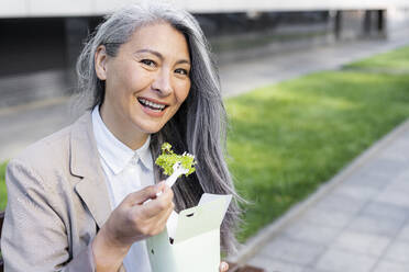 Smiling woman with gray hair holding food box - OIPF01305