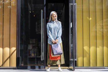 Frau mit Einkaufstüten vor dem Eingang eines Geschäfts - OIPF01329