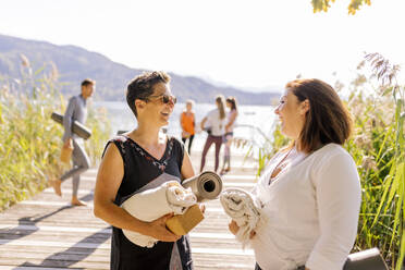 Frau mit Sonnenbrille im Gespräch mit Freundin beim Yoga-Kurs - DAWF02020