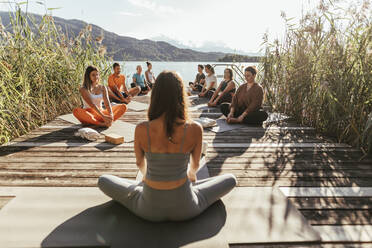 Female instructor teaching Baddha Konasana during yoga class - DAWF02043