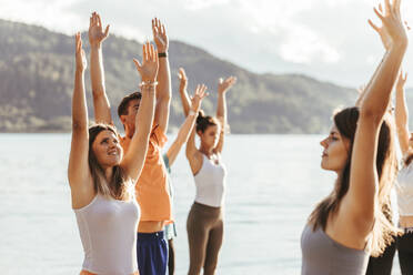 Weiblicher Yogalehrer mit Männern und Frauen beim Yoga an einem sonnigen Tag - DAWF02049