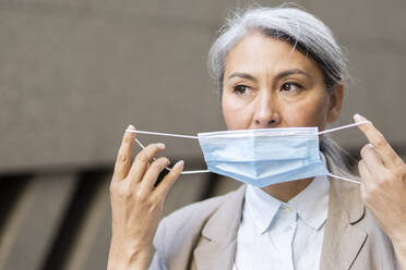 Mature woman wearing protective face mask during pandemic - OIPF01377