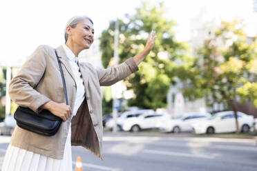 Ältere Frau mit Umhängetasche, die auf der Straße mitfährt - OIPF01382