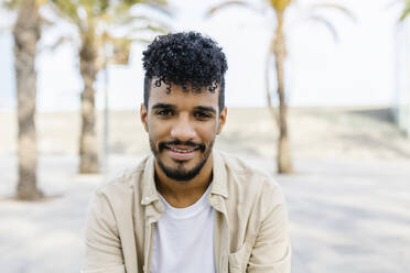 Smiling young bearded man with curly hair - XLGF02345