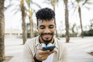 Happy young man sending voicemail through mobile phone - XLGF02352