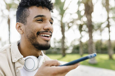 Smiling man with wireless headphones talking through speaker on