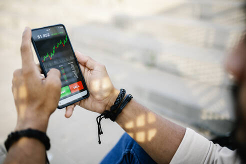 Man checking stock market graph through mobile phone - XLGF02378