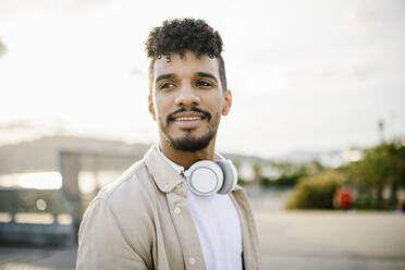 Young bearded man with black hair wearing wireless headphones - XLGF02389