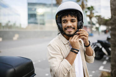 Young man wearing crash helmet on road - XLGF02395