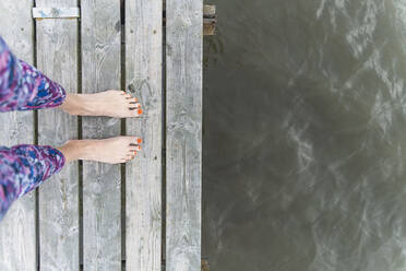 Mature woman standing on wooden pier by sea - CHPF00795