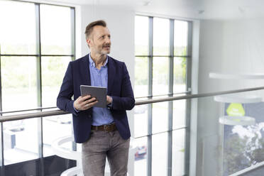 Männlicher Berufstätiger stehend mit digitalem Tablet am Flur im Büro - FKF04390