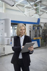 Weibliche Fachkraft arbeitet in einer Fabrik an einem digitalen Tablet - FKF04413