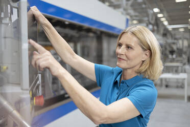 Blonde Frau bedient Maschinen in einer Fabrik - FKF04422