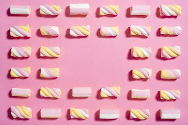 Studioaufnahme von Marshmallows flach gegen rosa Hintergrund mit leeren Raum in der Mitte gelegt - GPF00059