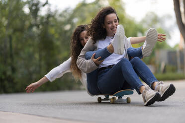 Fröhliche junge Freundinnen haben Spaß beim Skateboardfahren im Park - JPF00441