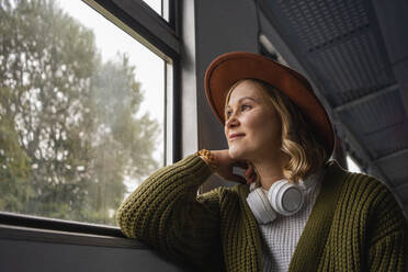 Woman looking through window while travelling in train - VPIF05111