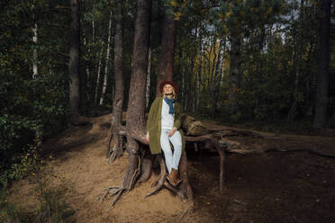 Mittlere erwachsene Frau sitzt an einem Baumstamm im Wald - VPIF05124