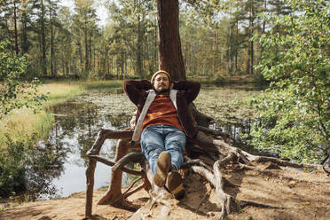 Man with eyes closed relaxing near tree in forest - VPIF05128