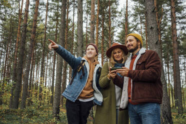 Junge zeigt auf Eltern, die im Wald ihr Smartphone benutzen - VPIF05135