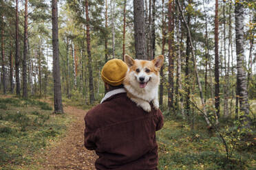 Man carrying dog on footpath in forest - VPIF05138