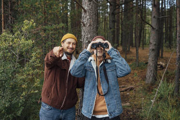 Vater gestikuliert in der Nähe eines Jungen, der im Wald durch ein Fernglas schaut - VPIF05145