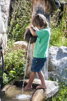 Junge mit nackten Füßen genießt in Wasser-Brunnen während sonnigen Tag - HHF05822