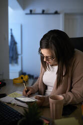 Businesswoman working on home finances at night - ZEDF04279