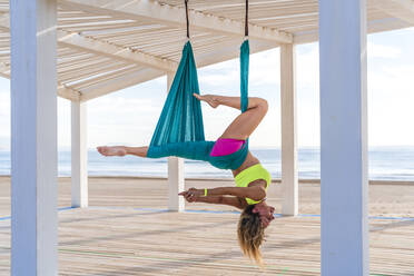 Flexible Akrobatin beim Training im Schatten am Strand - DLTSF02272