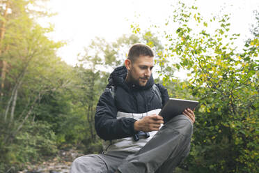 Männlicher Tourist benutzt digitales Tablet im Wald - JCCMF04327