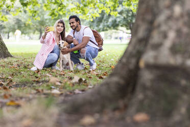 Lächelnde Frau macht Selfie mit Hund und Freund im Park - WPEF05352