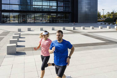 Young sportsman running with woman on footpath - IFRF01114